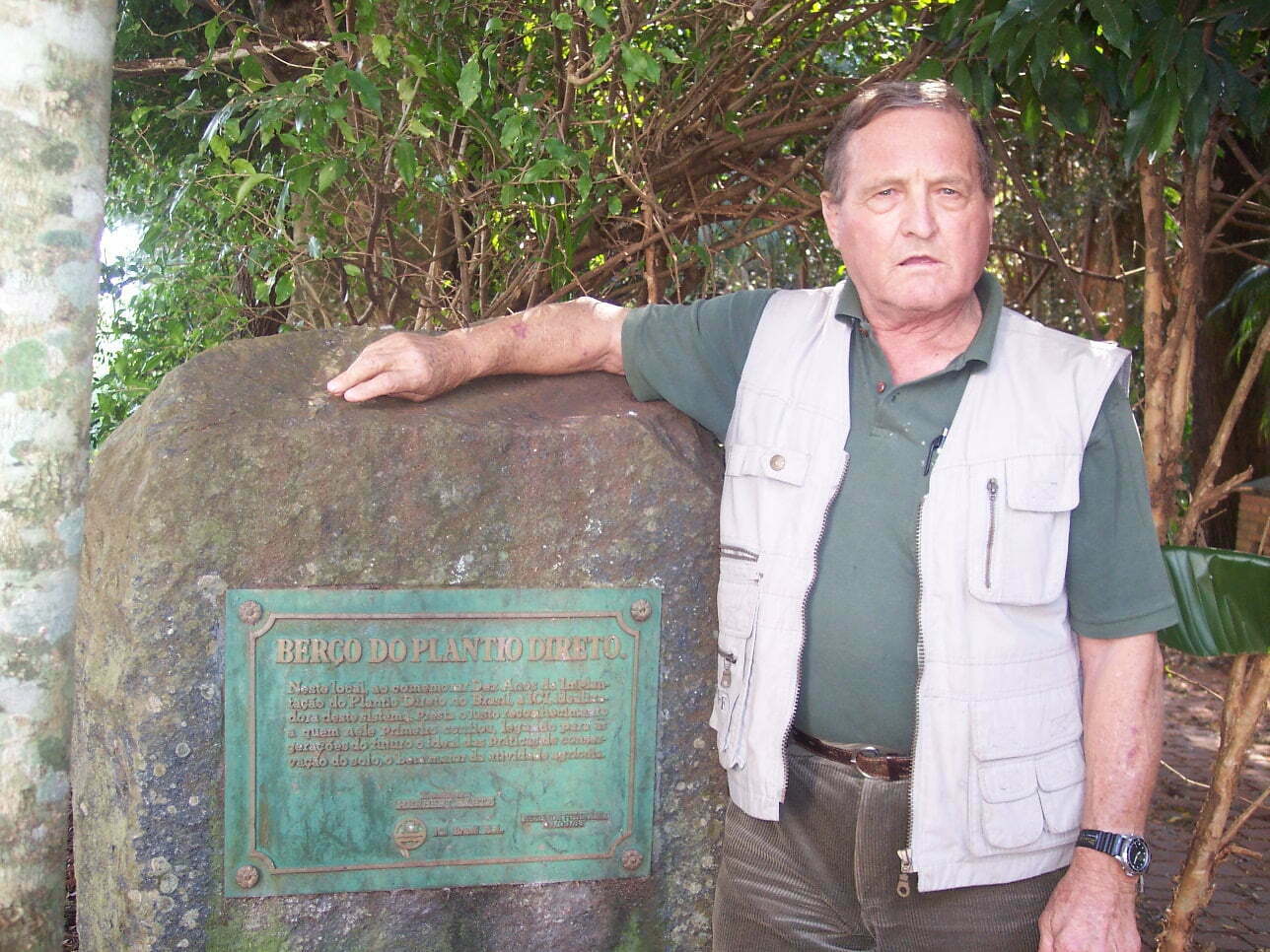 Herbert Bartz ao lado da placa de 1983 que marcou dez anos de PD no Brasil. No texto, um agradecimento ao primeiro produtor a confiar no sistema, "legando para as gerações do futuro o ideal das práticas de conservação do solo, o bem maior da atividade agrícola."