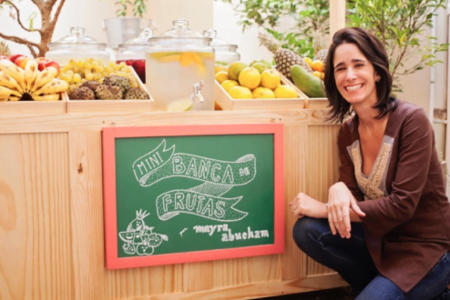 Mayra em frente à banca de frutas, em um dos eventos de sua consultoria.