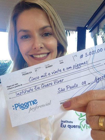 A atriz Bianca R mostra um cheque de doação da Piggme. Em dois anos, Jimmy estima ter ajudado mais de 5 mil crianças com as doações da startup.