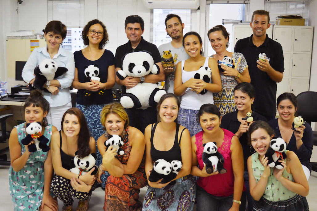 Equipe da Panda Books reunida na sede da editora segurando o mascote da editora.