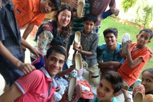 Leticia Sales (ao centro), cercada por garotos indianos que recebem doações de parte do lucro de sua marca de roupa, a Happee.