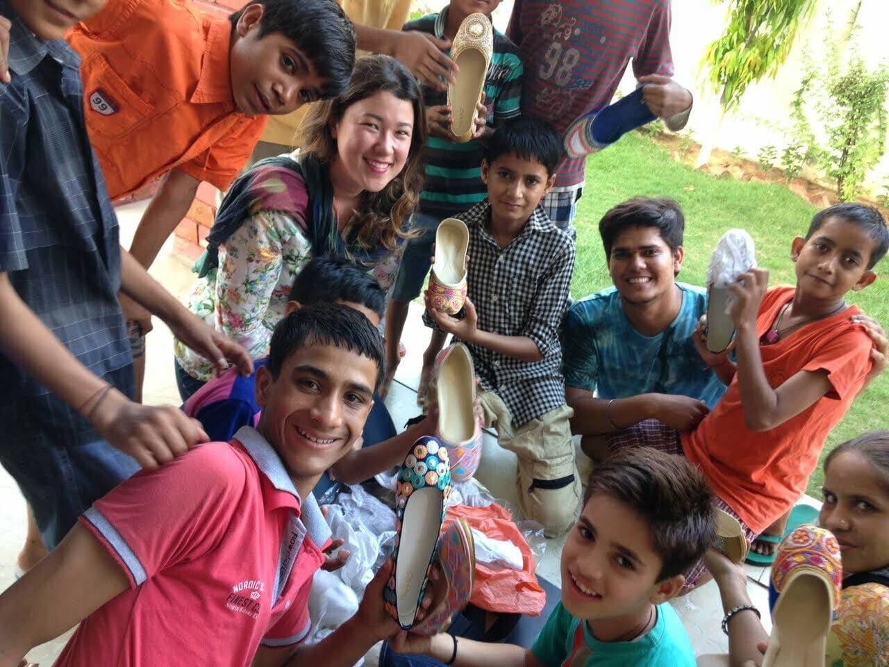 Leticia Sales (ao centro), cercada por garotos indianos que recebem doações de parte do lucro de sua marca de roupa, a Happee.