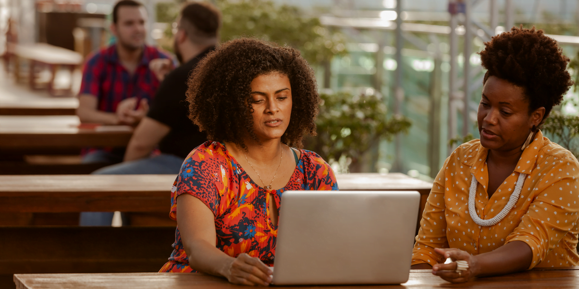 Duas mulheres negras, colaboradoras do CESAR, trabalham juntas em frente ao computador.